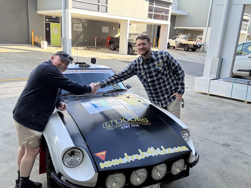 CAR240 team member thanking an LT Doors representative beside the rally car
